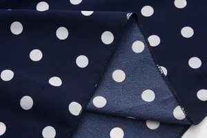Detail view of navy blue polka dot chiffon fabric with professional overlock stitching