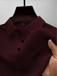 Gros plan sur la texture du tissu en maille bordeaux d'un polo à manches longues.