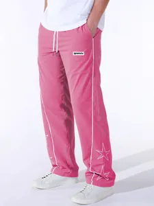 Detail showing men's pink sports pants with white star embroidery and side stripes