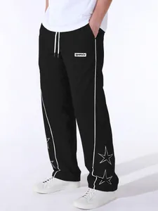 Close-up detail of men's black sports pants with white side stripes and star embroidery.