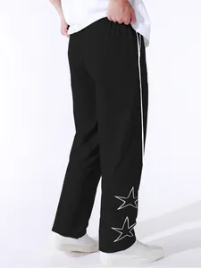 Detail of men's black leisure pants with white side stripe and embroidered star design