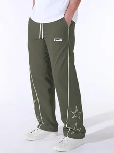 Detail of men's olive green sports pants with white star embroidery and side stripes