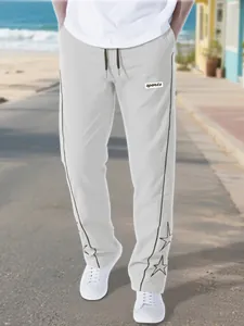 Detail view of men's high street grey sports trousers with star embroidery and side piping.