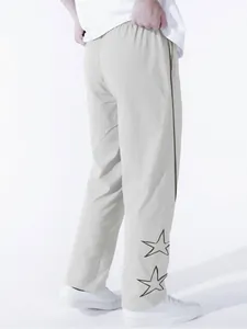 Detail view of light grey high street casual pants with embroidered star pattern