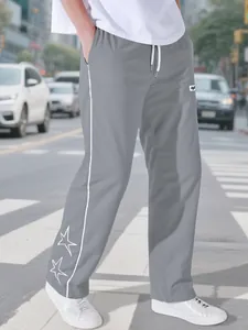 Close-up view of men's grey high street sports trousers featuring embroidered stars