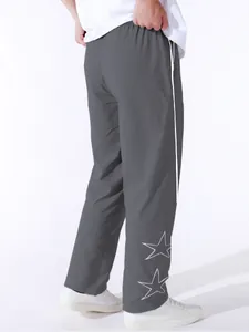 Detailed view of grey high street sweatpants featuring white star embroidery on the leg