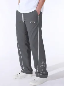 Close-up view of gray men's sports pants featuring side piping and star embroidery details