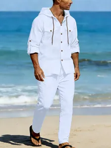 Detailed view of a white linen long sleeve hooded shirt and matching pants on a beach