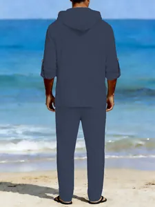 Back view of a casual men's navy blue linen hooded top and pants set on a beach