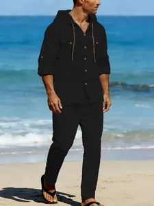 Full view of men's black linen casual suit worn by model on a sunny beach background