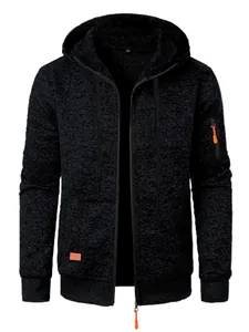 Close-up detail of a black jacquard knit hoodie featuring bright orange zipper accents