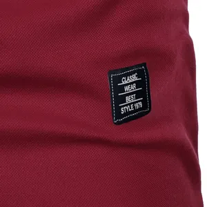 Close-up of black woven logo patch on men's burgundy slim fit summer short sleeve shirt