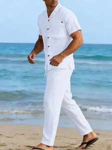 Model wearing a white linen short sleeve shirt and matching trousers on a sunny beach