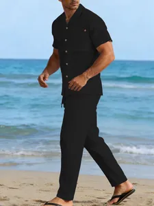 Detail view of men's black linen summer outfit worn by a model on a sunny beach background