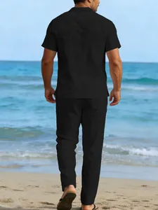 Back view of a man walking on a beach wearing a black linen casual shirt and trousers set