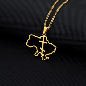 Macro detail of gold Ukraine map pendant with trident cross on black textured background