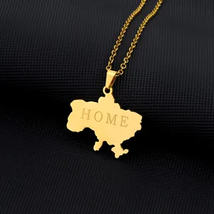 Close-up of gold Ukraine map pendant with HOME engraving on black textured background