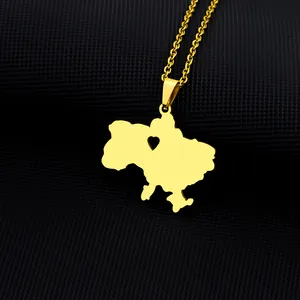 Detail of gold Ukraine map necklace with a hollow heart on a textured black surface