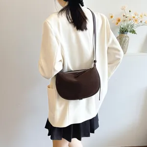 Dark brown frosted suede crescent crossbody bag worn by model in lifestyle setting
