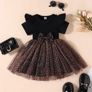 Detailed view of girl's leopard print mesh dress with black ribbed top and bow decoration.