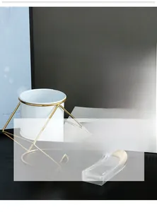 Close-up of Nordic style ceramic flower pots with gold geometric iron frames.