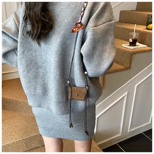 Back view of a vintage brown suede mini crossbody coin purse worn with a grey knit