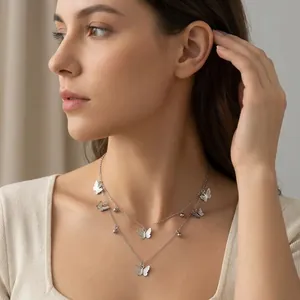 Close-up of a double-layered silver butterfly necklace with delicate charms on a model.
