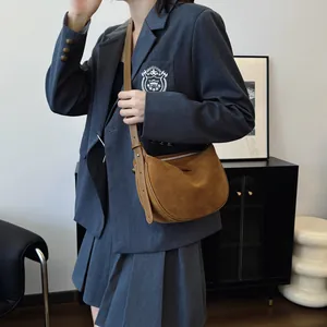 A minimalist brown suede hobo bag being worn as a stylish underarm crossbody dumpling bag