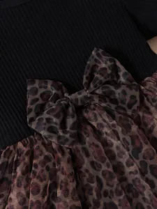 Close-up detail of a leopard print mesh bow on a black ribbed cotton girls' dress