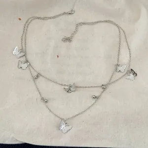 Detailed macro view of a double-layered silver necklace featuring butterfly charms