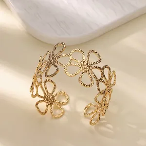 Detailed view of a gold-tone titanium steel bangle with hollowed-out daisy floral patterns.