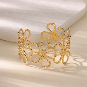 Macro detail of elegant gold hollow flower cuff bracelet with hammered texture finish