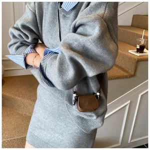 Detail view of a vintage suede mini crossbody coin purse on a grey knitted dress