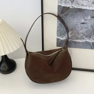 Detail view of a brown suede underarm bag with a minimalist design and silver zipper.