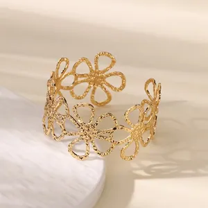 Detailed macro view of golden hollowed-out daisy cuff bracelet with textured finish
