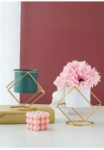 Close-up of modern geometric gold iron stand with green and white plant pots