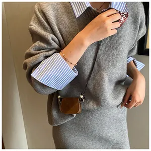 Model wearing a vintage brown suede mini crossbody bag over a gray knitted sweater detail