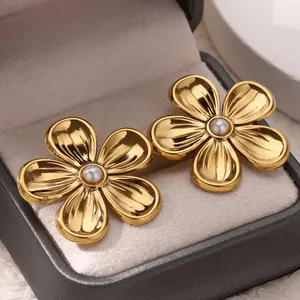 Macro detail of gold titanium steel daisy earrings with elegant pearl center inlay