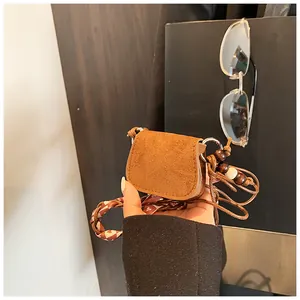 Detailed view of a retro brown suede mini crossbody bag with a stylish beaded strap