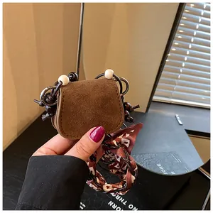 Close-up of vintage brown suede mini coin purse with decorative scarf-wrapped strap.