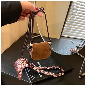 Detail view of a vintage brown suede mini coin purse featuring a decorative scarf strap