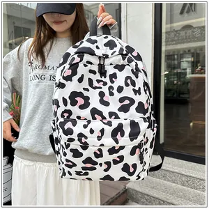 Detail of a white leopard print backpack with pink accents held by a female model