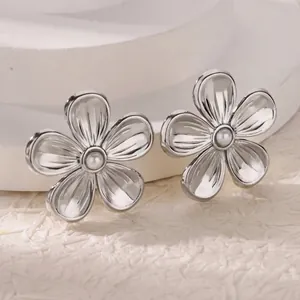 Macro view of silver hollow daisy stud earrings featuring a central white pearl
