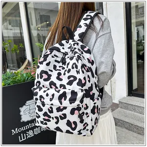 Close-up view of a model wearing a stylish white leopard print backpack in an outdoor setting