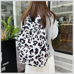 Detailed back view of a stylish white leopard print backpack worn by a student in a city setting