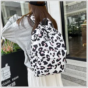 Fashionable white backpack with black and pink leopard print worn by a woman outdoors.