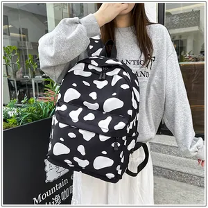 Detailed view of stylish cow print school backpack worn by a model in street style setting