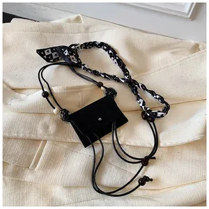 Close-up of a vintage black suede mini coin purse featuring a stylish patterned scarf handle.