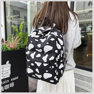 Stylish black and white cow pattern backpack for students shown in outdoor lifestyle setting