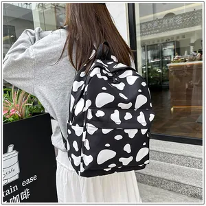 Casual black and white cow print backpack shown on model's back in a street setting
